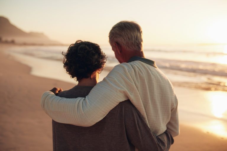 äldre par går längs stranden